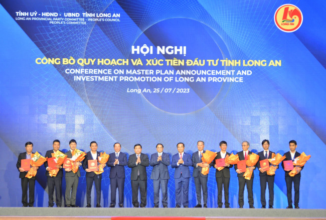 Prime Minister Pham Minh Chinh and provincial leaders congratulate businesses receiving investment certificates at the conference announcing investment planning and promotion of Long An