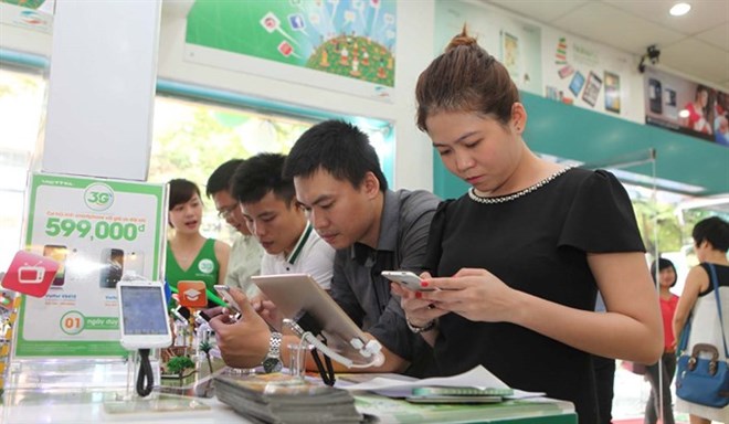 Shoppers test out different mobile devices at a Viettel store on Ng​oc Kh​anh Street, H​anoi (Photo: VNA)