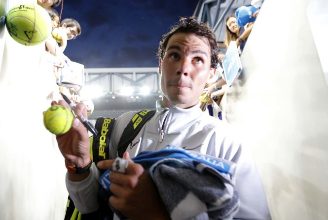 Nadal ký tặng CĐV sau chiến thắng trước Dzumhur. Ảnh: Reuters