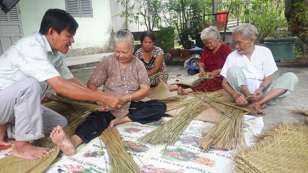 Ông Dương Văn Đạt hướng dẫn cách đan bao, đệm bàng cho các thành viên tổ hợp tác