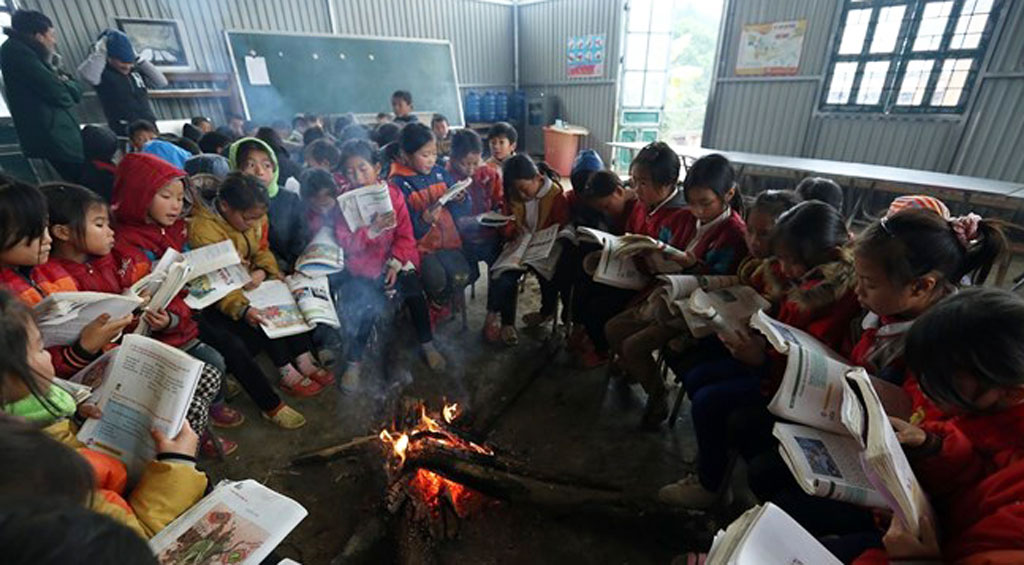 Học sinh nội trú trường Tiểu học Tỏa Tình, huyện Tuần Giáo, Điện Biên ngồi ôn bài bên đống lửa sưởi ấm trong những ngày giá rét. (Ảnh: Phan Tuấn Anh/TTXVN)