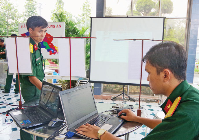 Đại úy Nguyễn Hữu Nghị (bên trái) thao tác phần mềm quản lý đạn dược trang bị kết nối kiểm tra lên màn hình