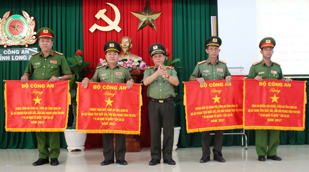 Thượng tá Phạm Thanh Tâm - Trưởng Công an huyện Cần Giuộc (bìa phải), nhận cờ thi đua xuất sắc cấp cơ sở của Bộ Công an
