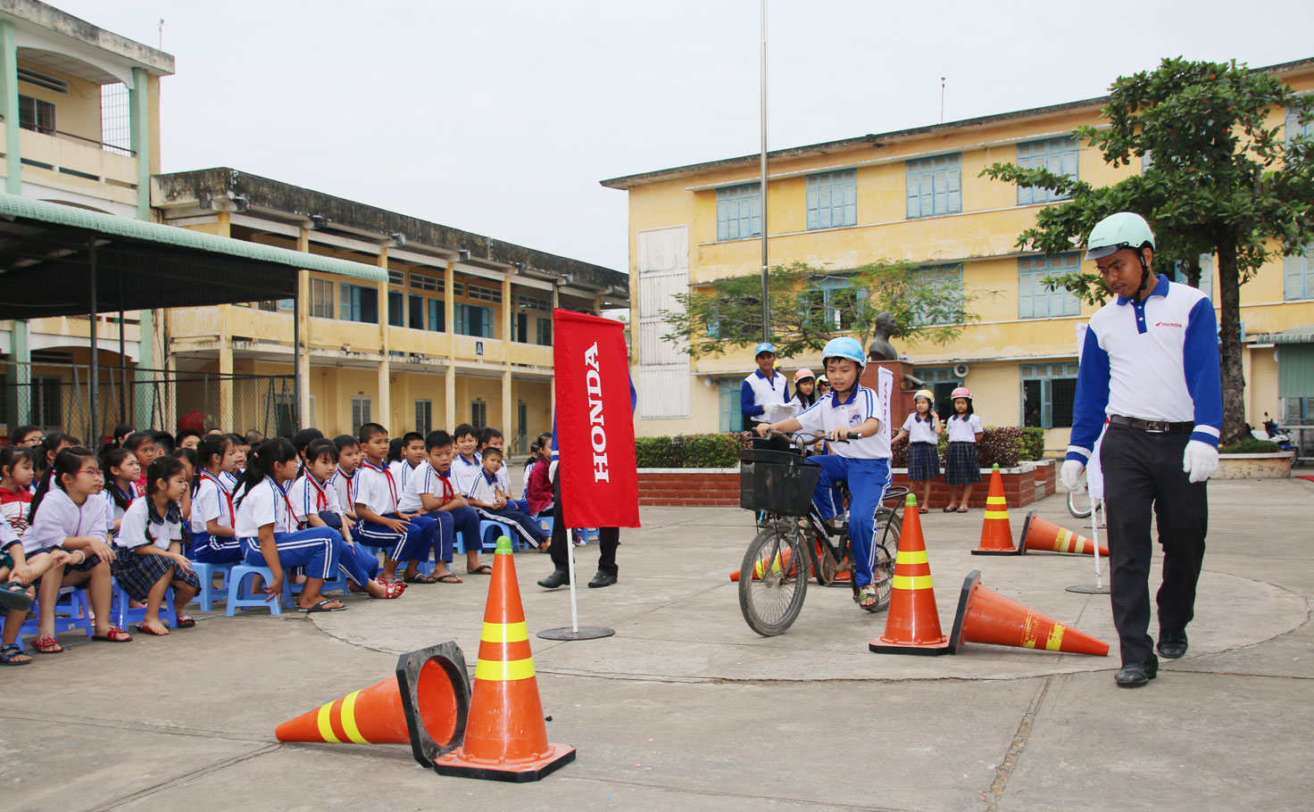 Nhân viên Công ty TNHH Thương mại - Dịch vụ Honda Tâm Phong hướng dẫn học sinh lái xe an toàn và đội nón