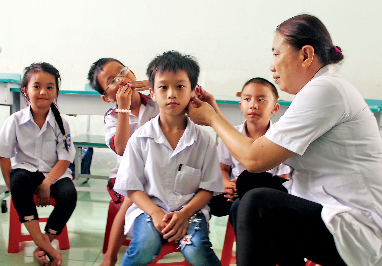 Bà Lê Phạm Hoa Anh Đào kiểm tra máy trợ thính cho trẻ em khuyết tật