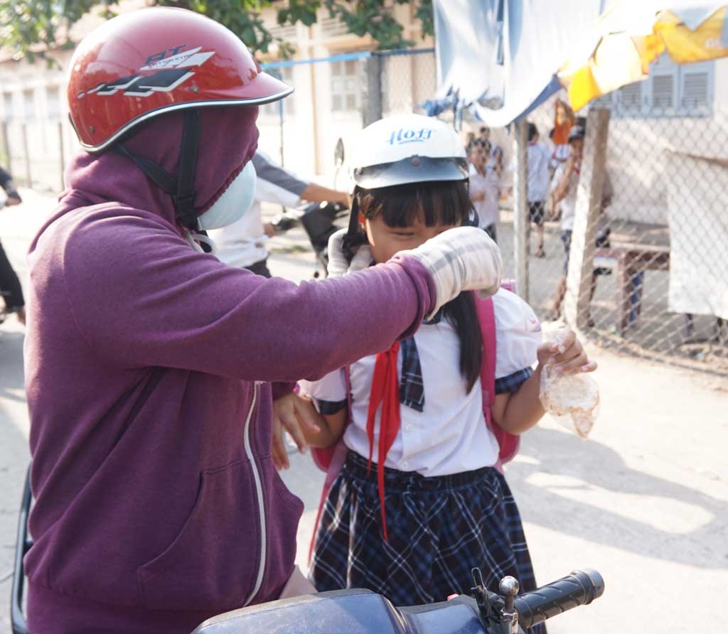 Đội mũ cho con trọn tình cha mẹ (Ảnh chụp tại Trường Tiểu học thị trấn Bến Lức)