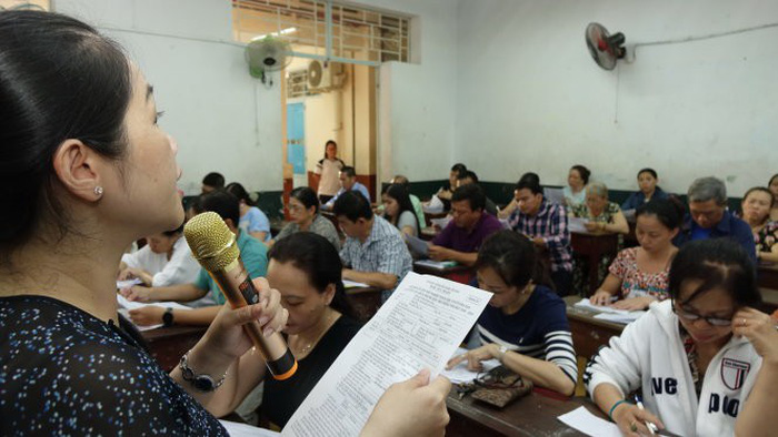 Giáo viên Trường THCS Kim Đồng, Q.5, TP.HCM phổ biến cách ghi hồ sơ dự thi cho phụ huynh - Ảnh: N.H.
