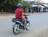 Người đàn ông ngồi sau để bé gái điều khiển xe máy chạy băng băng trên đường