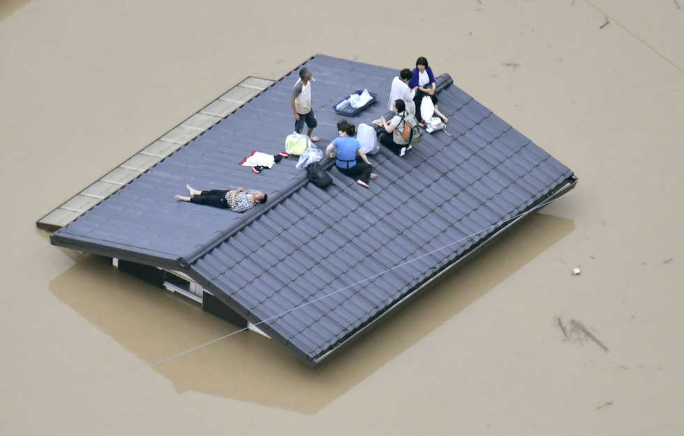 Người dân phải trèo lên mái nhà do nước lụt và chờ lực lượng giải cứu tại TP Kurashiki, phía nam Nhật, ngày 07/7 - Ảnh: Reuters