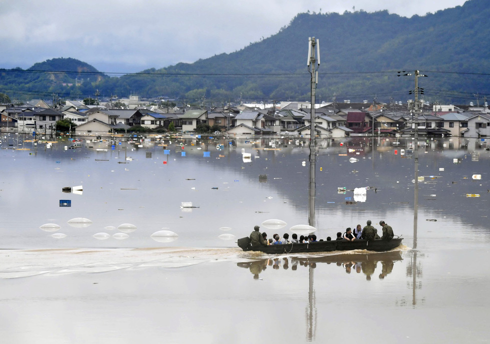 Lực lượng phòng vệ Nhật dùng xuồng nhỏ di tản người dân bị ảnh hưởng vì mưa lũ ở TP Kurashiki, phía nam Nhật, ngày 07/7. Nước sông dâng lên khiến khu vực này như một cái hồ lớn - Ảnh: Reuters