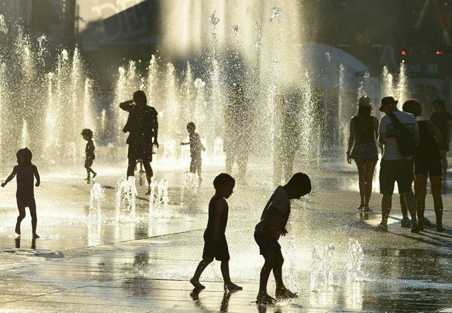 Trẻ em chơi đùa bên vòi phun nước để tránh nắng nóng tại Montreal, Canada ngày 03/7. (Nguồn: AFP/TTXVN)