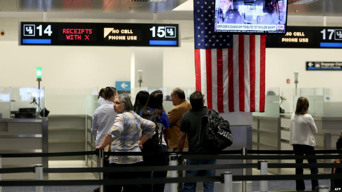 Du khách quốc tế xếp hàng chờ làm thủ tục tại khu vực kiểm soát hải quan sau khi tới sân bay quốc tế Miami ở Florida - Ảnh: AFP