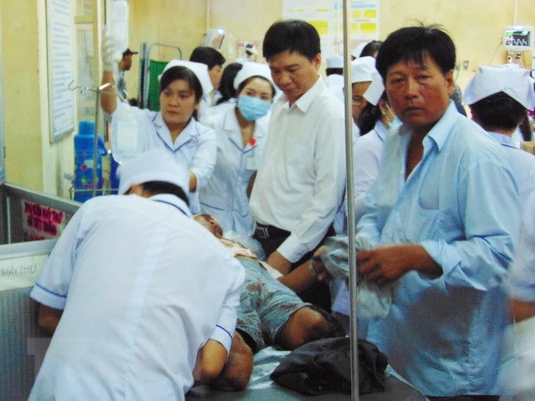 Ông Nguyễn Bình Tân (mặc áo sơmi trắng đứng giữa), Bí thư huyện Vĩnh Lợi đến thăm hỏi nạn nhân đang điều trị tại Bệnh viện Đa khoa Bạc Liêu. (Ảnh: Huỳnh Sử/TTXVN)