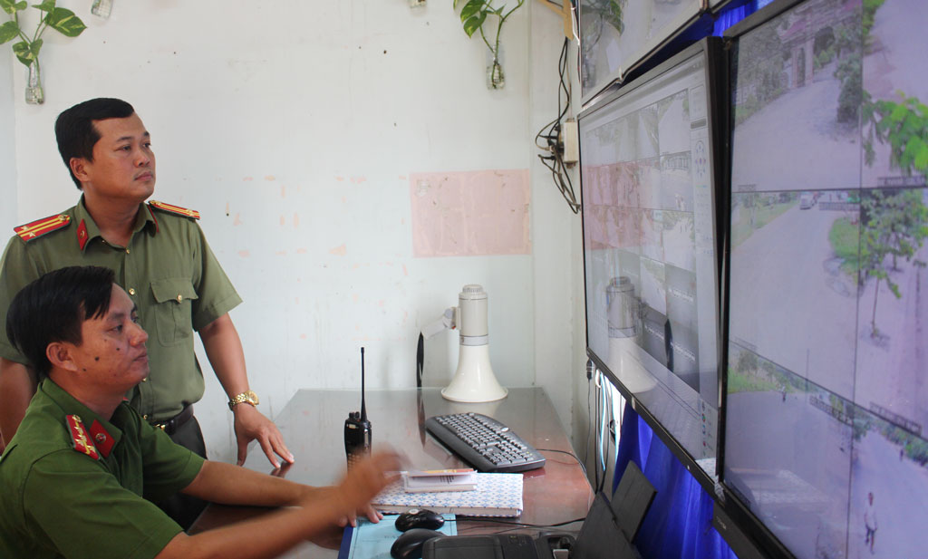 Đại úy Lê Tấn Dư (ngồi) kiểm tra thông tin tội phạm qua camera giám sát an ninh, trật tự