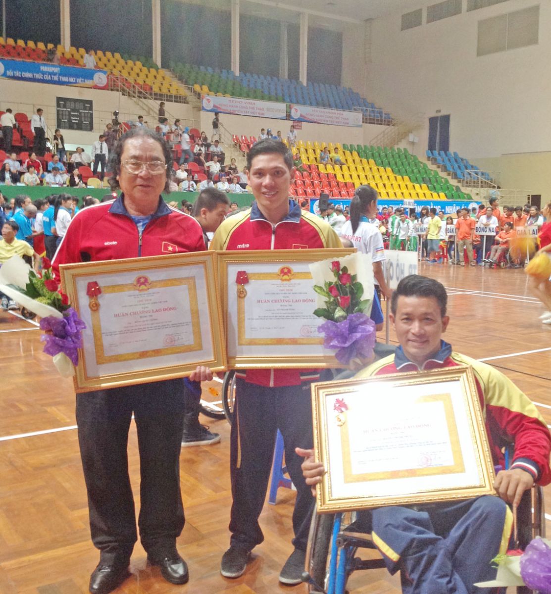 Huấn luyện viên Đổng Quốc Cường cùng 2 học trò Võ Thanh Tùng, Nguyễn Thành Trung (ngồi xe lăn) nhận Huân chương Lao động hạng Nhì