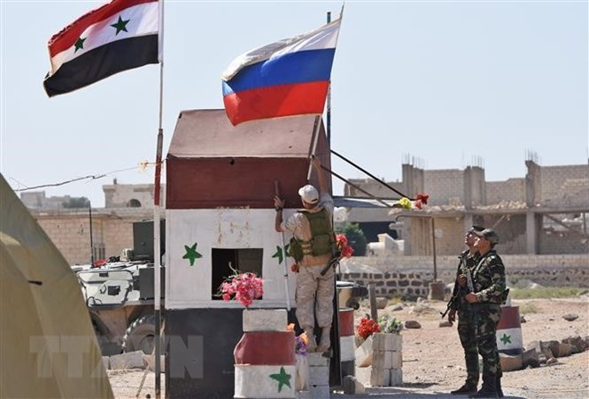 Cờ Syria (trái) và cờ Nga tại khu vực Abu Duhur, tỉnh Idlib. (Nguồn: AFP/TTXVN)