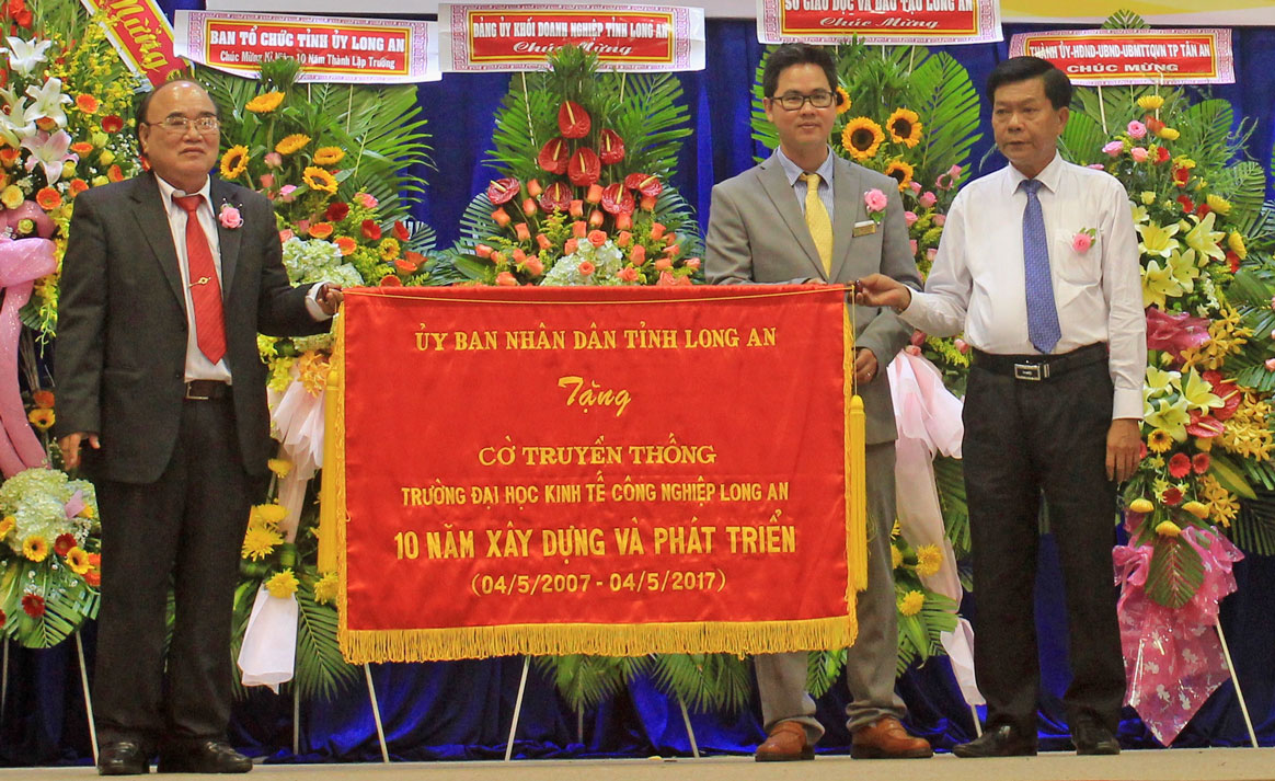 Chủ tịch UBND tỉnh - Trần Văn Cần (bìa phải) trao cờ truyền thống cho Trường DLA