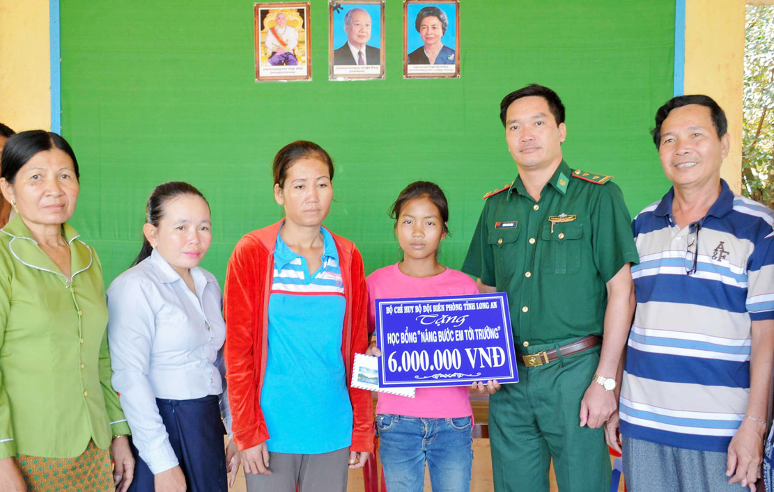 Trung tá Hoàng Văn Dũng - Chính trị viên Đồn Biên phòng Bến Phố tặng học bổng cho học sinh huyện Svay Chrum, tỉnh Svay Rieng, Vương quốc Campuchia, có hoàn cảnh khó khăn vươn lên trong học tập