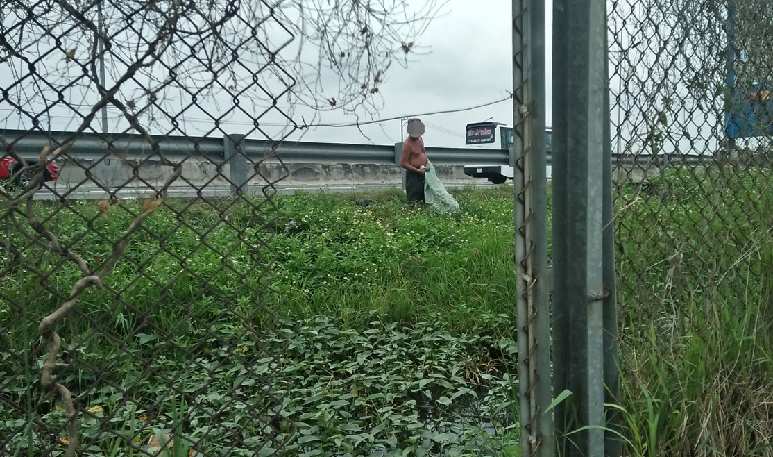 Một người đàn ông đi qua lối hàng rào bị cắt phá vào trong khu vực đường cao tốc