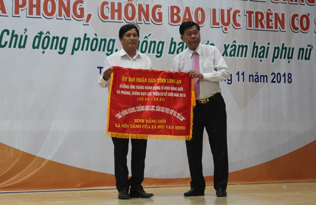 Chủ tịch UBND tỉnh - Trần Văn Cần (bìa phải) trao cờ phát động Tháng hành động Vì bình đẳng giới