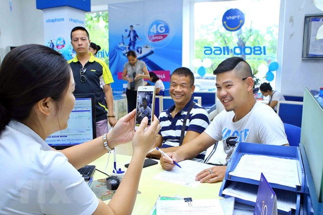 Nhân viên chụp ảnh chân dung khách hàng đến đăng ký thuê bao trả trước mới tại Trung tâm kinh doanh VNPT Vinaphone Hà Nội. (Ảnh: Minh Quyết/TTXVN)