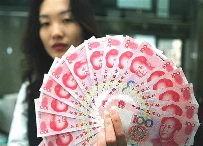 Nhân viên ngân hàng kiểm tiền giấy mệnh giá 100 nhân dân tệ mới của Trung Quốc. (Ảnh: AFP/TTXVN)