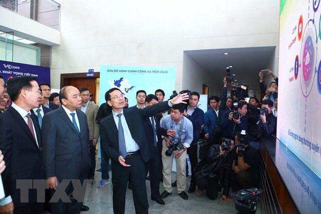 Bộ trưởng Bộ Thông tin và Truyền thông Nguyễn Mạnh Hùng thuyết minh với Thủ tướng Nguyễn Xuân Phúc và các đại biểu tham quan triển lãm sản phẩm về công nghệ số. (Ảnh: Minh Quyết/TTXVN)