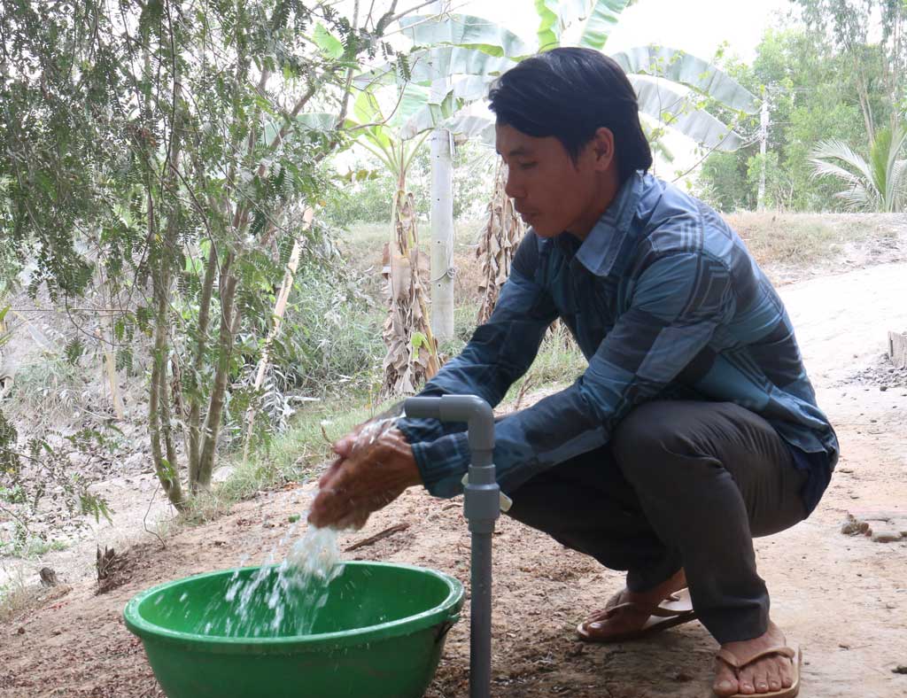 Người dân nông thôn vui mừng khi sử dụng nước sạch (Trong ảnh: ông Nguyễn Ngọc Diện, ngụ ấp Ông Nhan Đông, xã Bình Hiệp, thị xã Kiến Tường, phấn khởi khi được dùng nước sạch và công trình cấp nước ấp Ông Nhan Đông) Ảnh: Thanh Mỹ