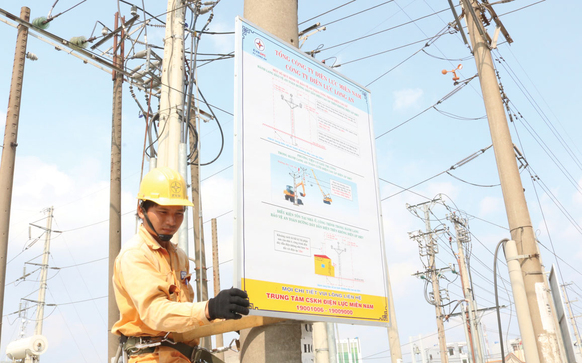 Nhân viên điện lực lắp panô tuyên truyền, phổ biến các quy định về bảo vệ hành lang an toàn lưới điện cao áp