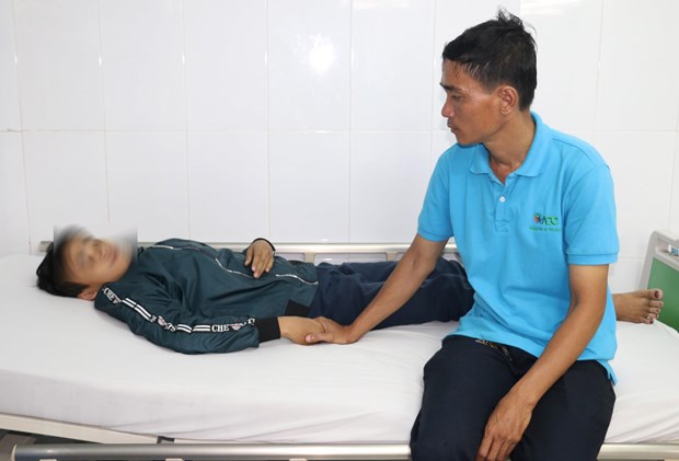 Anh Nguyễn Hữu Tri chăm sóc em Thọ tại Phòng cấp cứu Bệnh viện Sản nhi An Giang sau khi bị nhóm bạn học cùng trường đánh hội đồng. (Ảnh: Công Mạo/TTXVN)