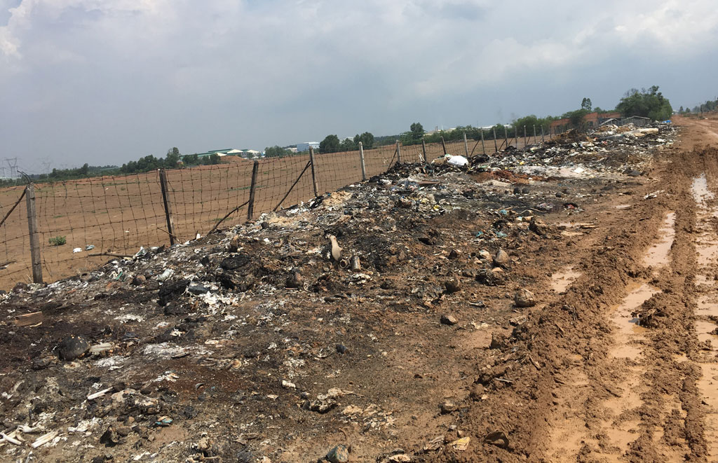 Waste is disposed without regulations and burnt at the fence of the Hanh Phuc IP along Kenh Tay road