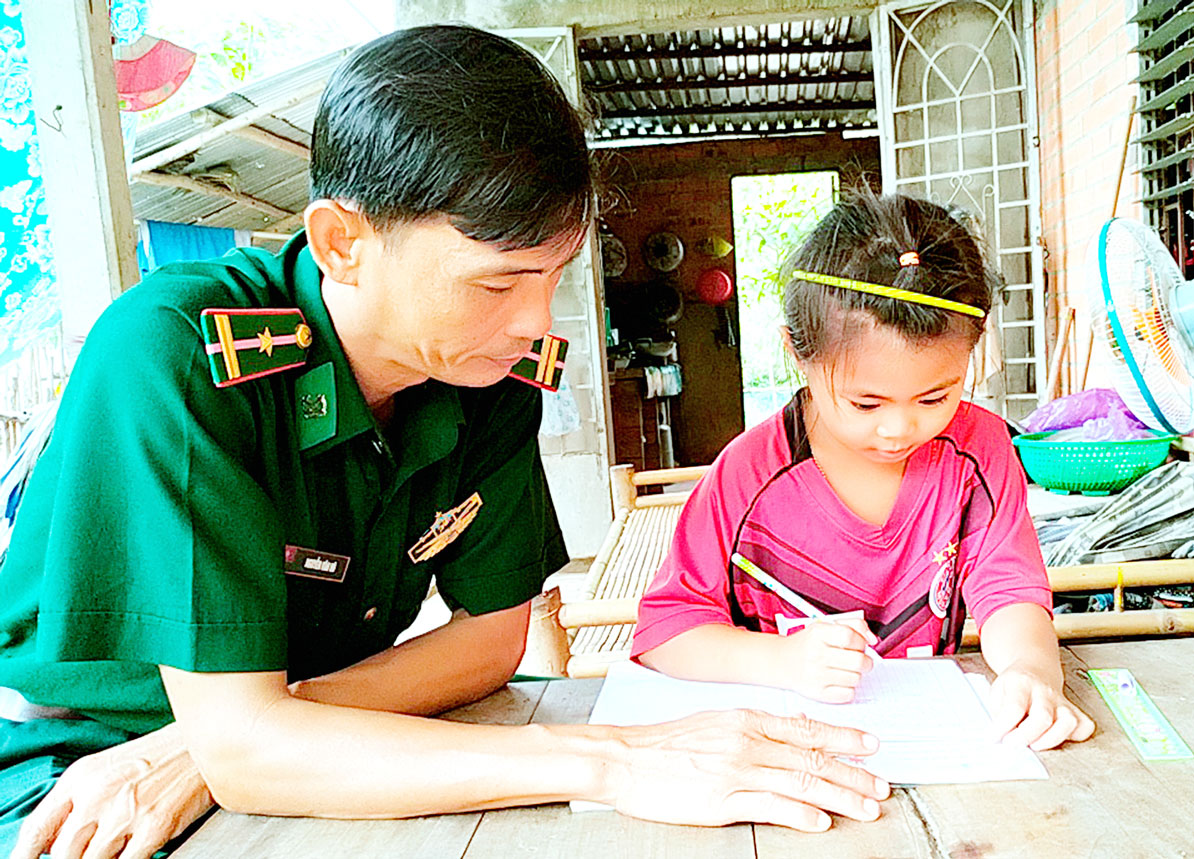 Mô hình “Con nuôi đồn biên phòng” - nuôi dưỡng ước mơ đến trường Thiếu tá Nguyễn Văn Hô hướng dẫn em Lê Nguyễn Cát Tường học bài