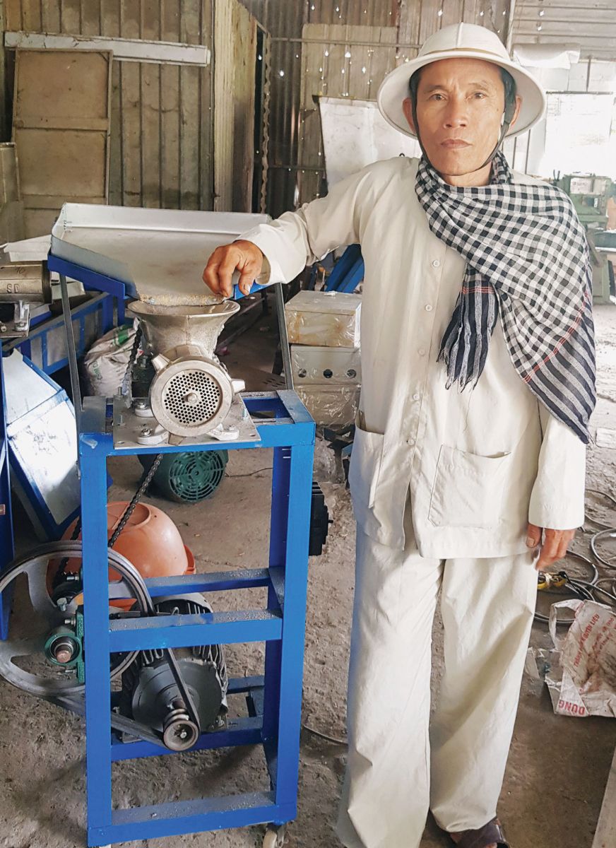 Ông Đinh Văn Sơn bên sản phẩm máy ép sấy cám viên của mình