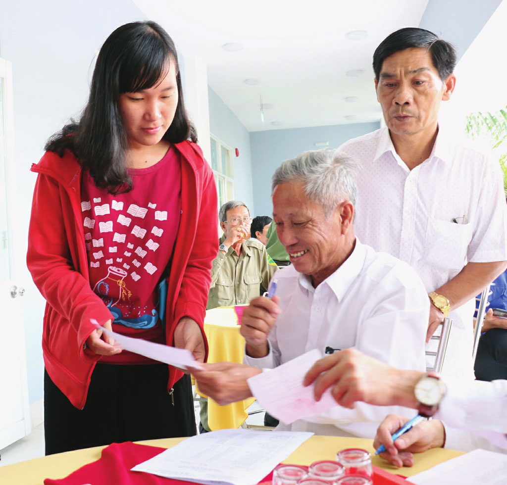 Ông Nguyễn Văn Triều (giữa) kiểm tra một số thông tin để chuẩn bị phát quà cho người có hoàn cảnh khó khăn 