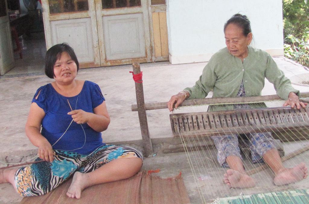 Làng nghề dệt chiếu Long Cang - Vượt khó để giữ nghề Bà Nguyễn Thị Năm cùng người cháu khuyết tật đang dệt chiếu