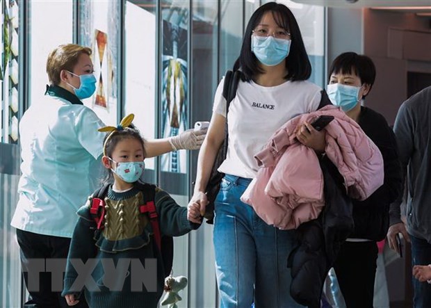 Nhân viên y tế Singapore theo dõi thân nhiệt hành khách qua máy quét tại sân bay quốc tế Changi ngày 22/1/2020. (Ảnh: AFP/TTXVN)