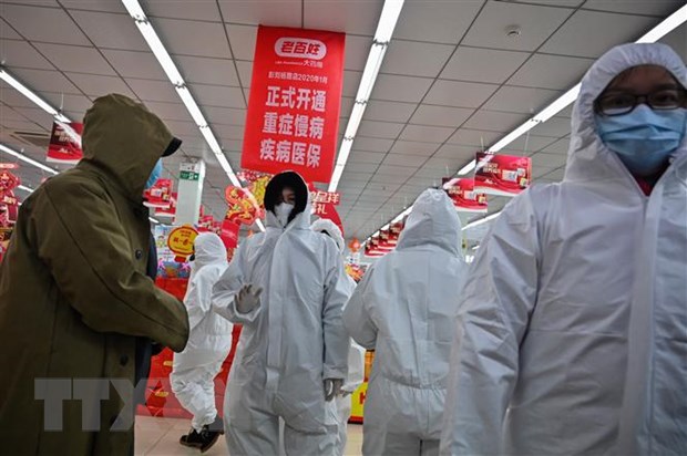 Nhân viên mặc quần áo bảo hộ và khẩu trang phòng chống dịch bệnh viêm phổi lạ do nhiễm virus corona phục vụ khách hàng tại một nhà thuốc ở Vũ Hán, Trung Quốc. (Ảnh: AFP/TTXVN)