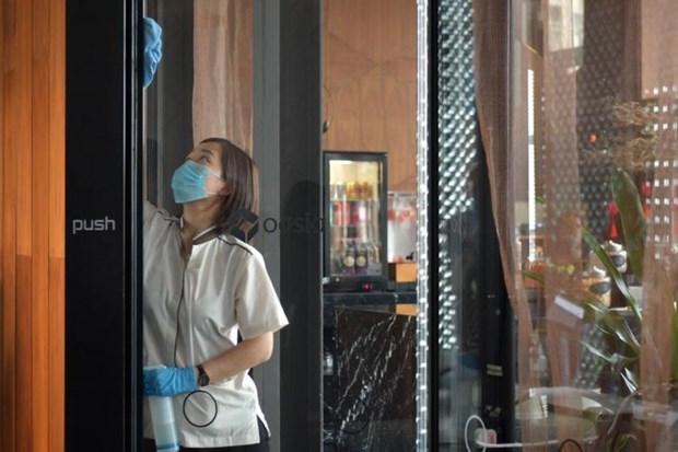 A cleaner at Oasia Hotel Downtown sanitizing the doors of the hotel's club lounge on Feb 2, 2020. (Photo: straitstimes.com)