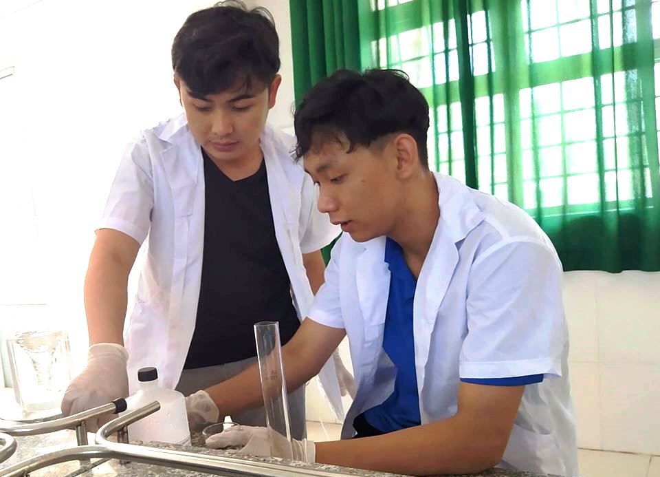 Anh Trương Trần Hoàng Du (bìa trái) hướng dẫn học sinh pha chế dung dịch sát khuẩn tay theo công thức WHO
