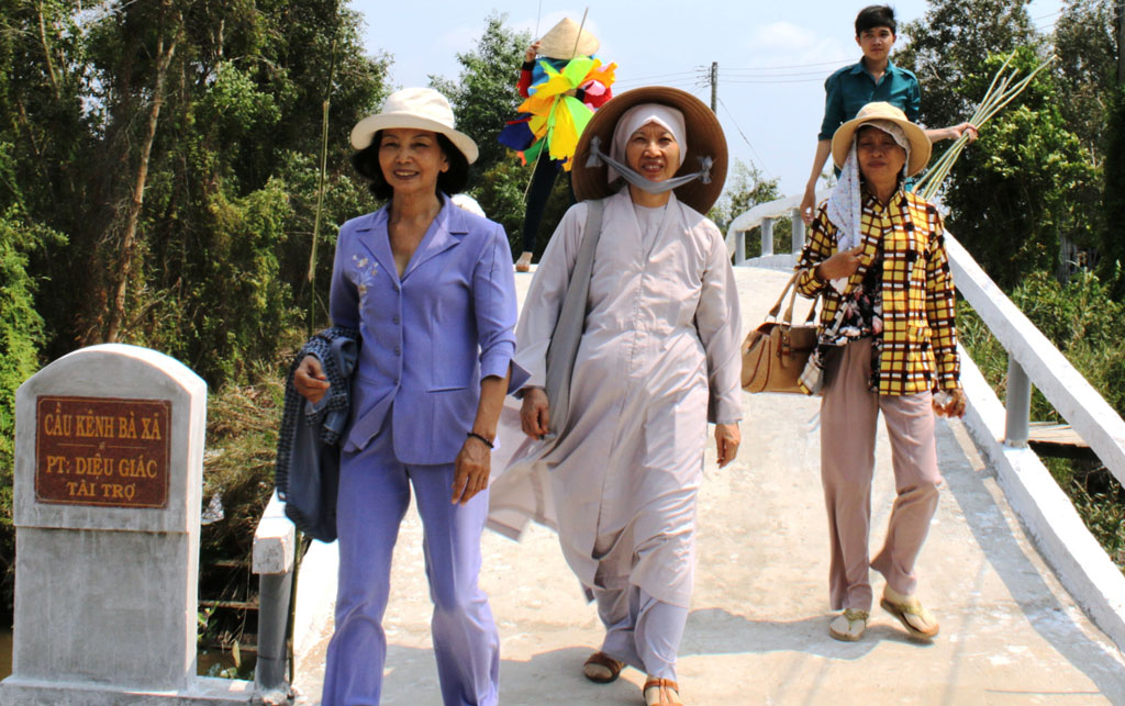 Bà Trần Thị Láng (bìa trái) đi trên cây cầu do mình vận động xây dựng