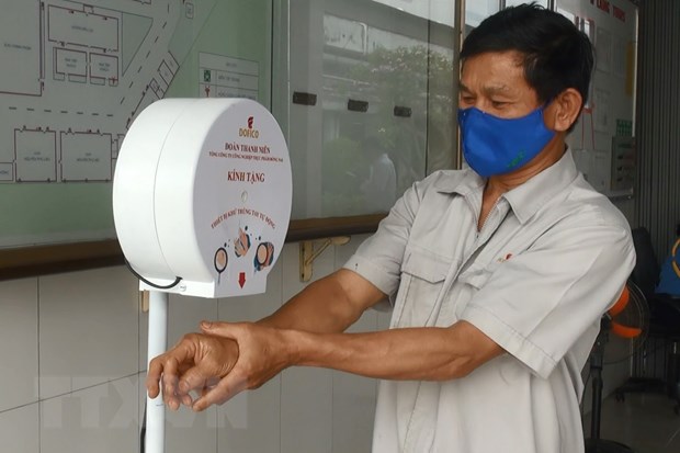 Công nhân Dofico sử dụng thiết bị rửa tay tự động chống COVID-19. (Ảnh: Lê Xuân/TTXVN)
