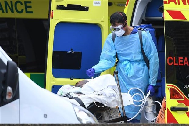 Nhân viên y tế chuyển bệnh nhân mắc COVID-19 từ xe cứu thương vào một bệnh viện ở London, Anh ngày 1/4/2020. (Ảnh: AFP/TTXVN)