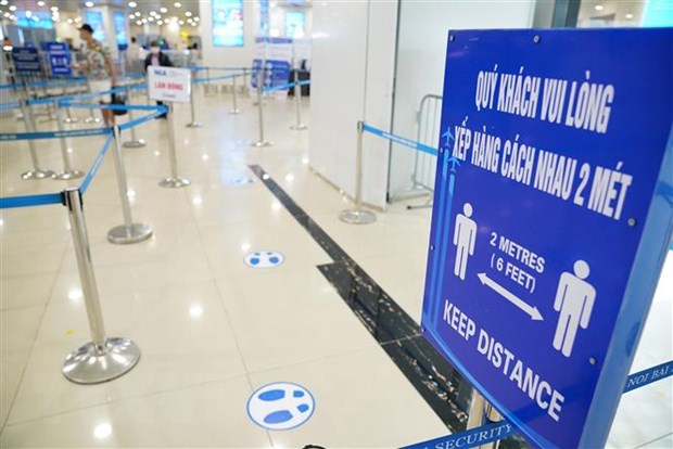 Biển báo nhắc nhở khách giữ khoảng cách tại các lối vào xếp hàng tại sân bay Nội Bài. (Nguồn: TTXVN)