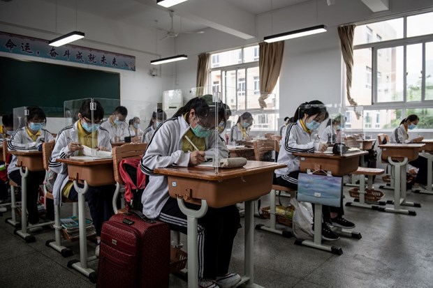 Học sinh đeo khẩu trang và ngồi bàn học riêng có tấm chắn tại Trung Quốc. (Nguồn: AFP)