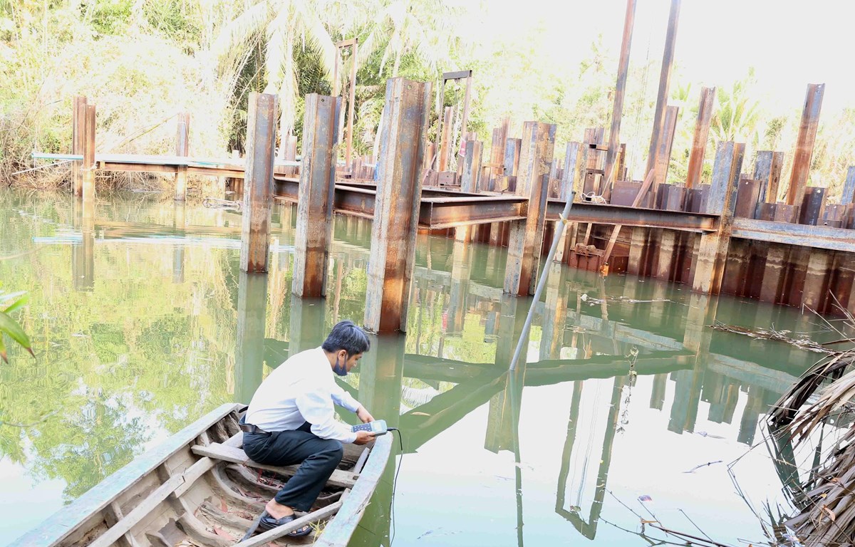 Cán bộ kỹ thuật của Sở Nông nghiệp và Phát triển nông thôn kiểm tra đo độ mặn tại đập ngăn mặn tạm thời trên sông Hàm Luông, xã Đông Sơn, thành phố Bến Tre. (Ảnh: Vũ Sinh/TTXVN)