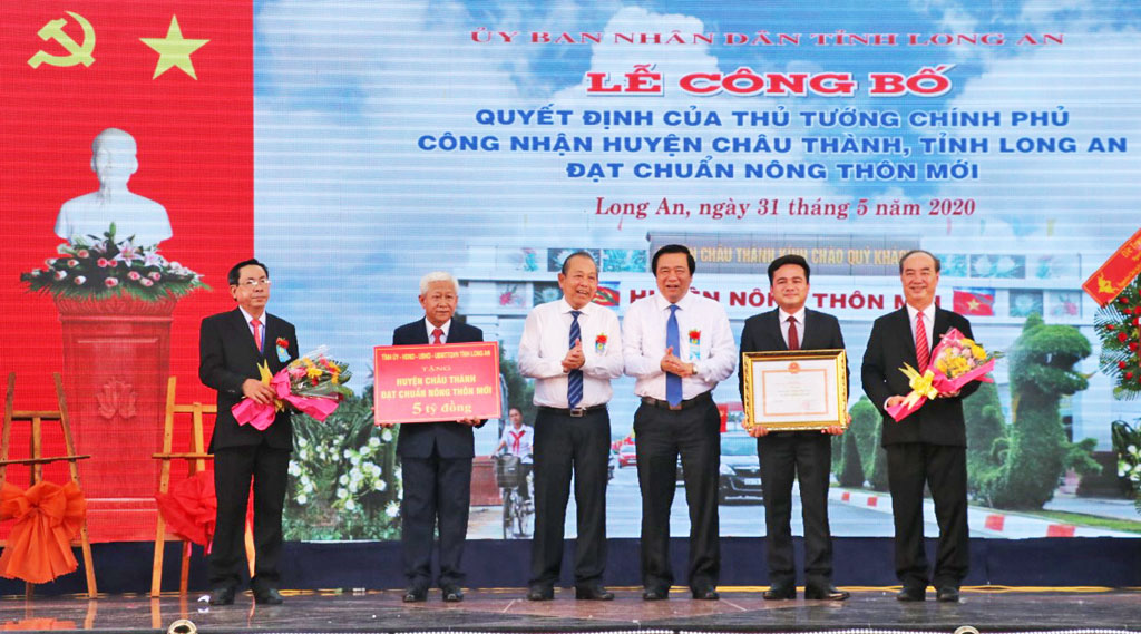 Standing Deputy Prime Minister - Truong Hoa Binh (3rd, L); Secretary of the Provincial Party Committee, Chairman of Long An People's Council - Pham Van Ranh (4th, L) hands over the Prime Minister's decision to recognize Chau Thanh district of Long An province meeting the new-style rural standard for Chau district leaders