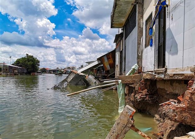 Vụ sạt lở làm phần nhà sau của 13 hộ dân sống ven sông Trà Nóc bị sụp hoàn toàn xuống sông. (Ảnh: Thanh Liêm/TTXVN)