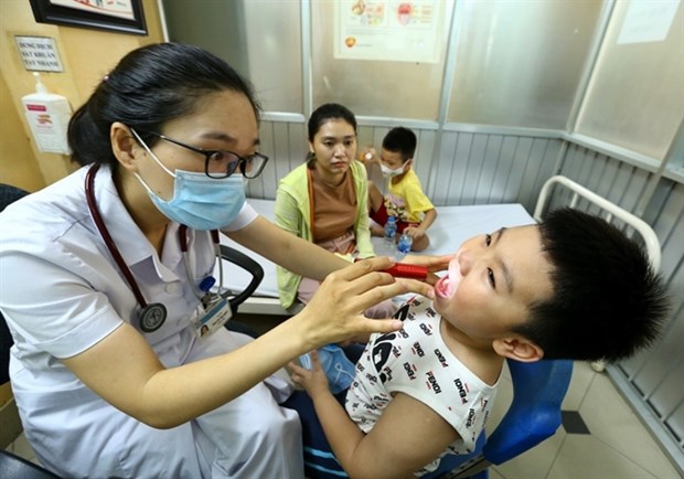 Prolonged hot weather causes health issues A doctor treats a boy at the Vietnam-Cuba Hospital's Paediatrics Department. (Photo: VNA)
