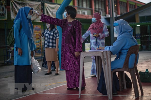 Kiểm tra thân nhiệt phòng lây nhiễm COVID-19 tại một trường học ở Kuala Lumpur, Malaysia. (Ảnh: AFP/TTXVN)