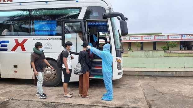 Tiếp nhận và kiểm tra thân nhiệt cộng đồng người Việt nhập cảnh để đưa về cách ly tập trung. (Ảnh: TTXVN phát)